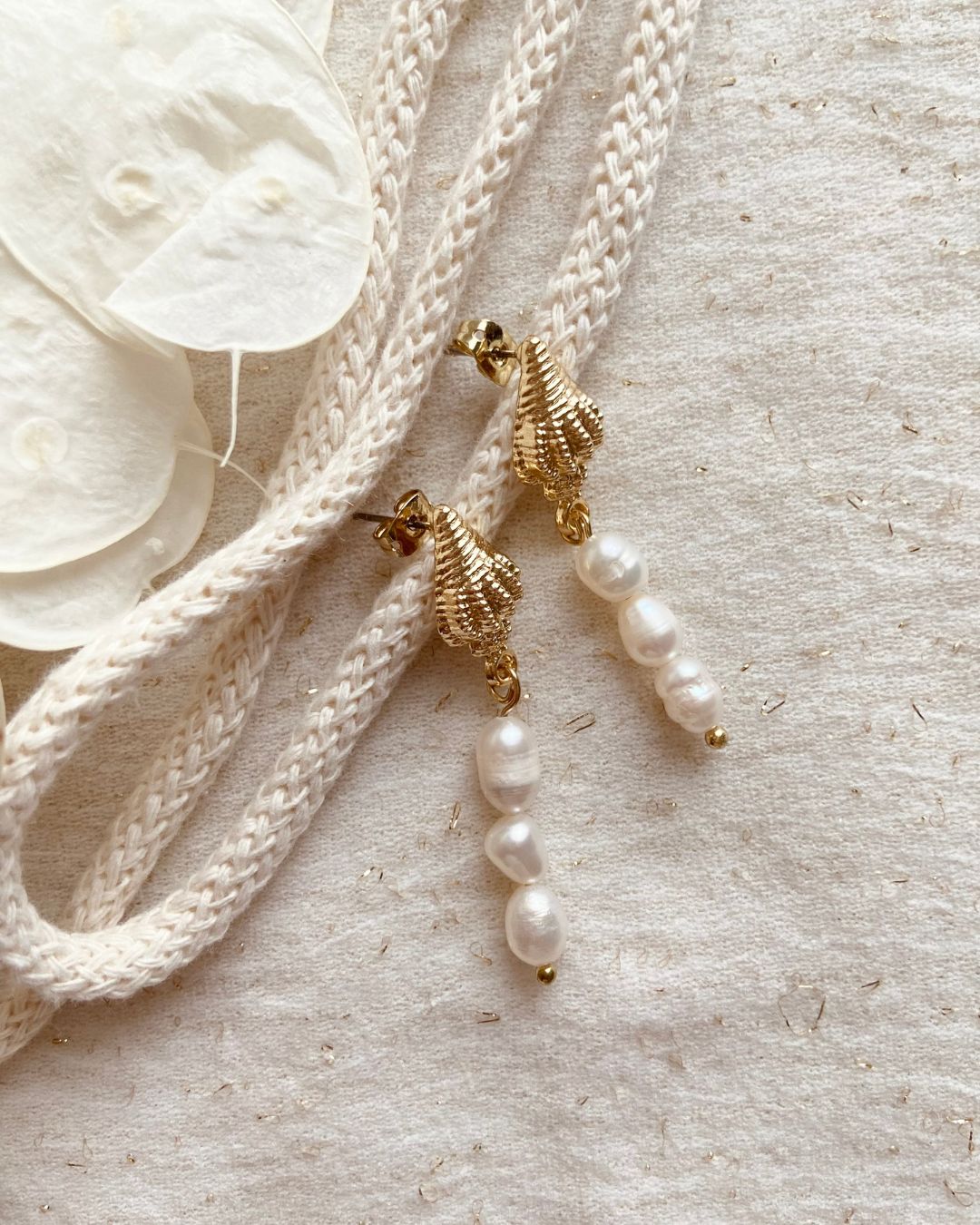 Boucles d'oreilles Mira composées d'une jolie puce en forme de coquillage doré et d'un pendentif de trois perles d'eau douces arrondies blanc nacrée réalisées à la main par la créatrice Johanne de Mes attrapes rêves