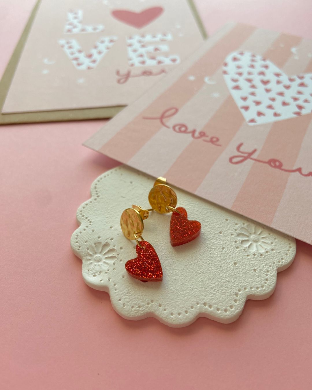 Boucles d’oreilles cœur rouge pailleté. Composées d’un pendentif cœur scintillant et d’un fermoir doré martelé, elles allient élégance et originalité pour sublimer toutes vos tenues.