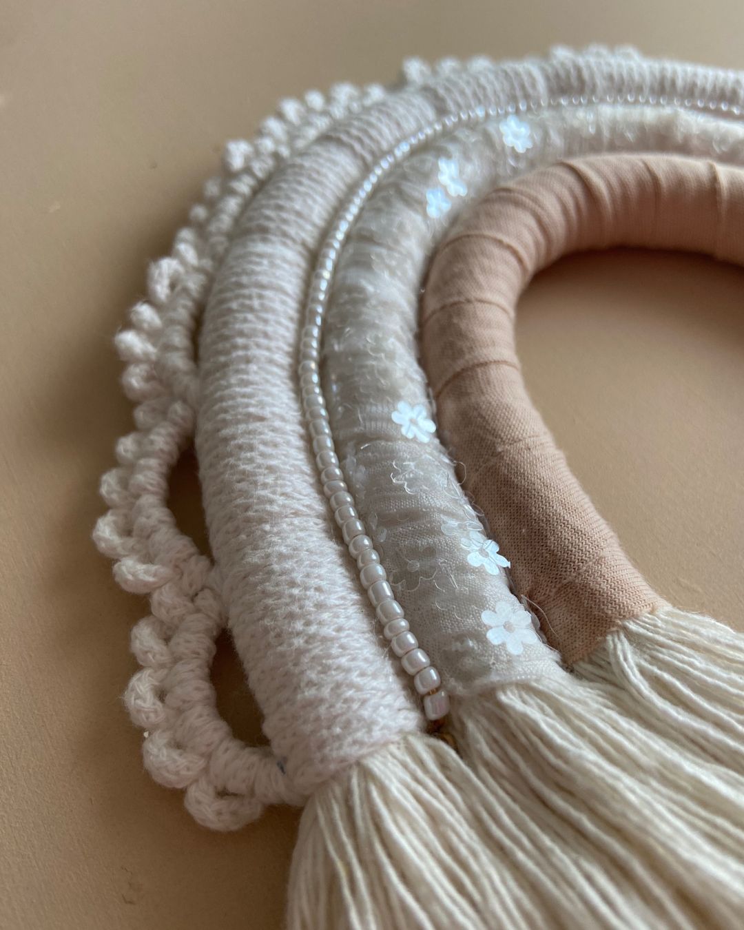 détail de l'arc-en-ciel tons neutres naturel et beige rosé avec détail macramé blanc réalisé à la main par Mes attrapes rêves