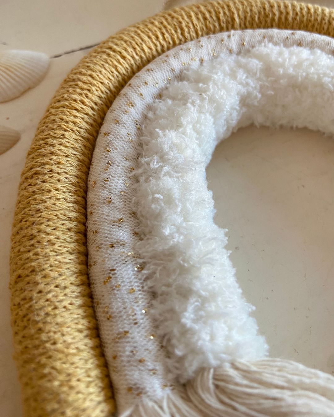 Détail de l'arc-en-ciel artisanal en laine moumoute blanche et laine moutarde et doré réalisé à la main par Mes attrapes Rêves
