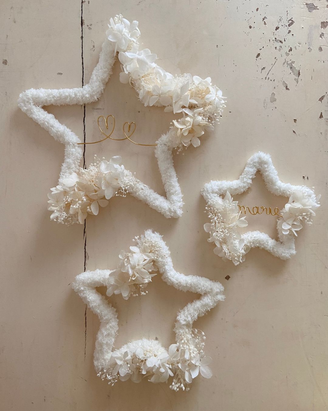Présentation des trois tailles de nos étoiles moumoute blanche, ornées de fleurs séchées blanches, modèle Ava, avec personnalisation– une création élégante et intemporelle signée Mes Attrapes Rêves.