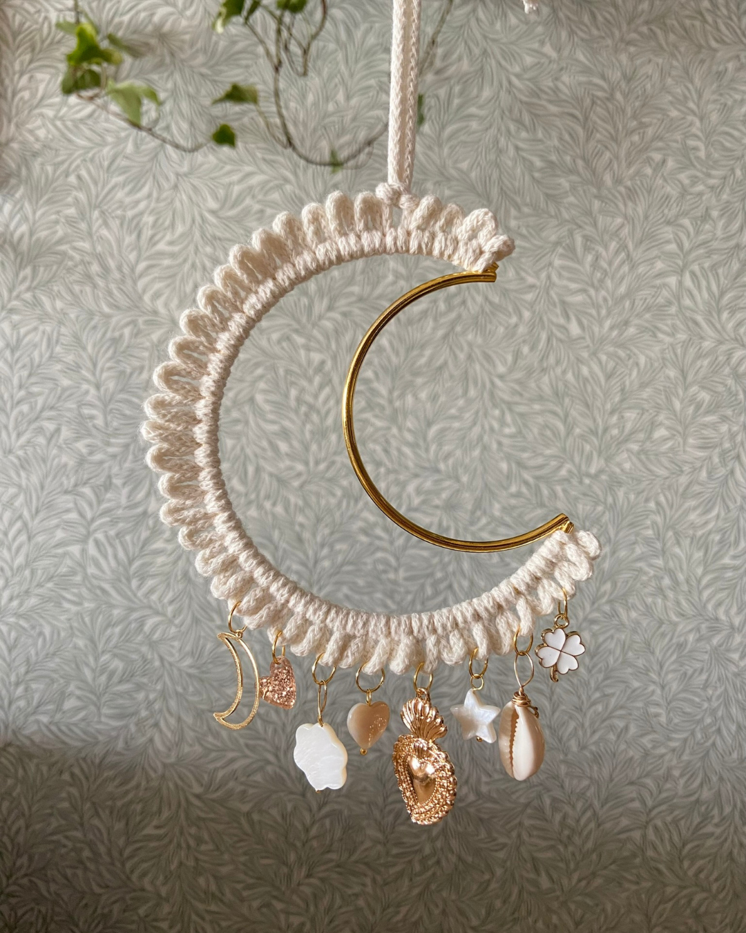 Grande Lune gri-gri écru - Bohème - Lune dorée en macramé et pampilles protectrices ✨🌙
Ajoutez une touche magique et artisanale à votre intérieur avec cette suspension attrape-rêves en forme de lune, entièrement fait main. Conçu avec un crochet délicat en coton, il est orné d’un croissant de lune doré ainsi que de magnifiques breloques protectrices symbolisant l’amour et l’énergie positive.