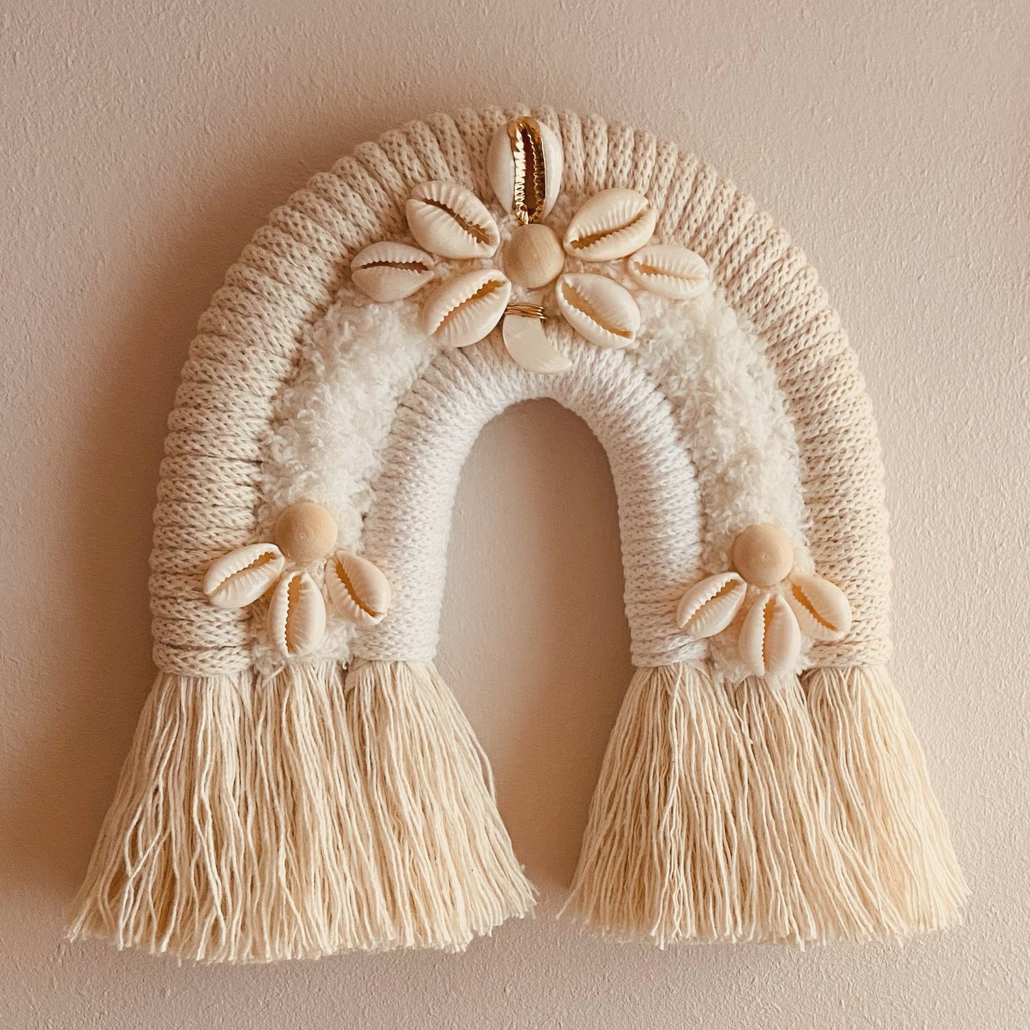Joli arc-en-ciel aux tons beiges naturels. Réalisé en corde beige, naturel et avec application de coquillages beigne et doré